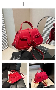 Detail of red pebbled leather handbag with curved flap and golden metal buckle closure