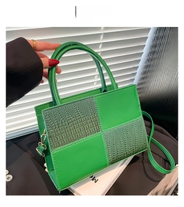 Détail d'un sac à main vert avec texture crocodile et poignées élégantes de luxe
