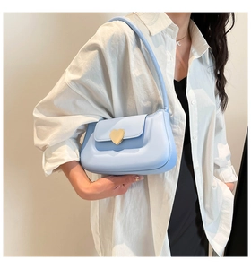 Close-up of light blue heart-shaped metal buckle on a minimalist leather shoulder bag