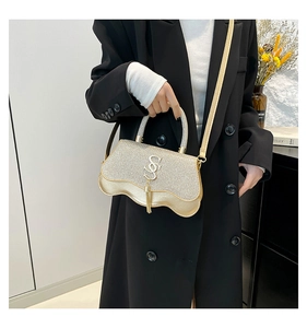 Detail of gold glitter crossbody bag featuring a wavy base and metallic tassel accent