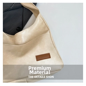 Detail view of cream beige leather tote bag with side pocket and brown logo patch