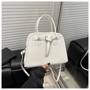 Detail of white PU leather handbag featuring a trapezoidal shape and metal buckle accent