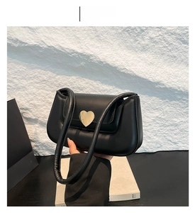 Dettaglio borsa nera con chiusura a cuore dorata e manico morbido imbottito