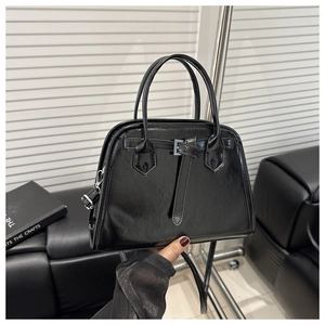 Detail of a black patent leather handbag with a strap buckle and metal hardware accents