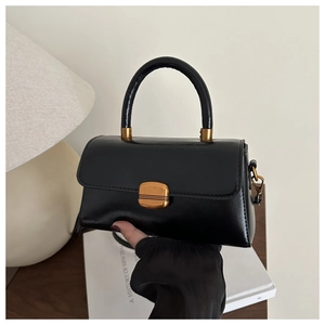 Détail d'un sac bandoulière vintage noir avec boucle dorée et finition en cuir texturé