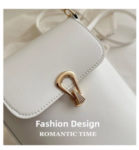 Close-up of minimalist white leather crossbody bag with golden horseshoe lock detail