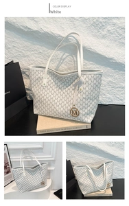 Detail view of white tote bag featuring M-letter monogram and gold metal charm pendant