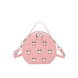 Chic pink round crossbody bag with silver sphere studs and top handle in a minimalist style