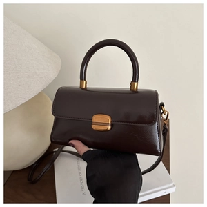 Détail d'un sac à main marron foncé en cuir vintage avec fermoir doré et poignée chic