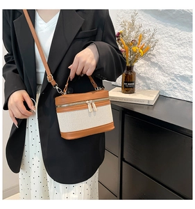 Close-up of retro canvas and brown leather bucket bag with dual zippers and textures