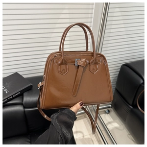Detail of a brown vintage trapezoid handbag in glossy PU leather with buckle strap