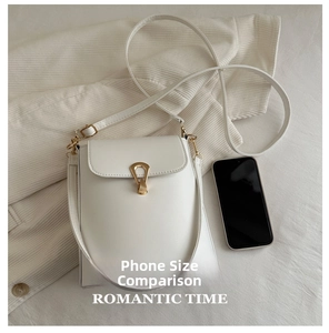 Detailed view of a white leather bucket bag with a golden horseshoe lock on corduroy
