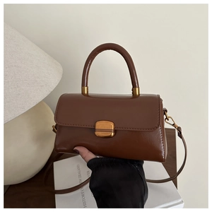 Détail du sac en cuir marron vintage avec fermoir doré rétro et poignée arrondie