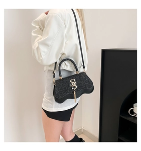 Detail of black sequined crossbody bag featuring wave bottom and gold S-shaped pendant
