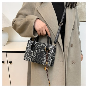 Detailed macro of leopard print handbag featuring a black top handle and textured finish