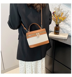 Detail of canvas and brown leather crossbody bag shown on model with shoulder strap