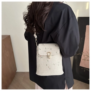 Dettaglio della borsa a tracolla in paglia beige con ricamo floreale verde e fibbia dorata