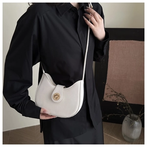 Détail d'un sac demi-lune blanc avec fermoir rotatif en métal doré et fine bandoulière