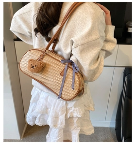 Detail of woven straw shoulder bag with brown leather trim and cute bear charm pendant