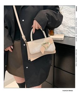 Detail of beige square bag with silver glitter flap and gold D-shaped buckle