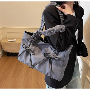 Gray ruched nylon tote bag with bow details worn with a blazer and jeans outfit