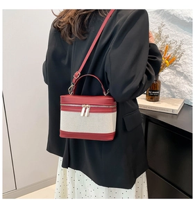 Detail of red leather and beige canvas contrast stitching on a stylish cylinder bucket bag