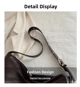 Detail view of large brown shoulder bag with silver buckles and polished leather surface