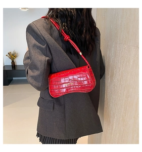 Red crocodile texture shoulder bag with wavy bottom shown on model in minimal room