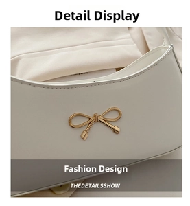 Detailed close-up of cream leather shoulder bag featuring a gold bow metal buckle