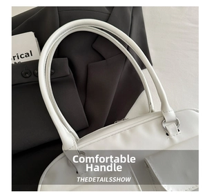 Detail of white handbag featuring long top handles, metallic rings, and a zipper closure
