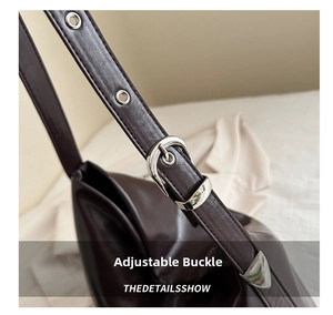Detail of adjustable shoulder strap with silver buckle on dark leather tote bag