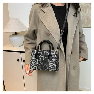 Detailed view of a leopard print crossbody bag worn with a beige wool coat in a home setting