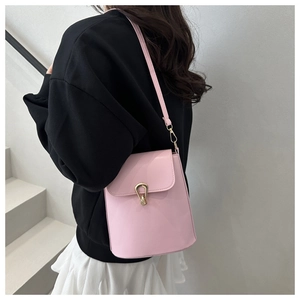 Detailed view of pink leather bucket bag featuring a unique gold metal buckle and strap