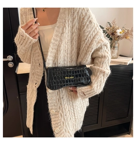 Detail of black faux leather shoulder bag with crocodile texture and Miss mini lettering