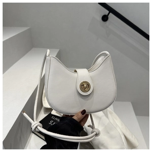 Détail du sac demi-lune en cuir blanc avec fermoir rotatif doré et bandoulière tressée
