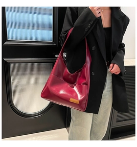 Detail of burgundy faux leather tote bag with brown label showing Hobo style draping