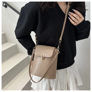 Close-up of beige crossbody phone bag featuring a gold horseshoe clasp and adjustable strap