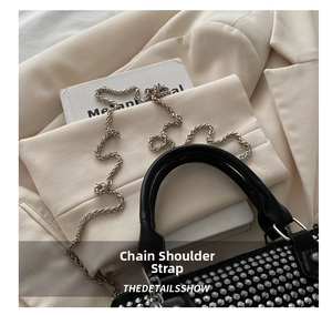 Close-up of black leather bag with silver studs and polished metal chain strap details