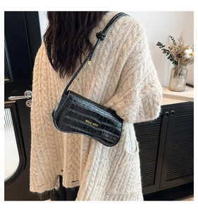 Close-up of black crocodile pattern shoulder bag with gold Miss mini logo detail