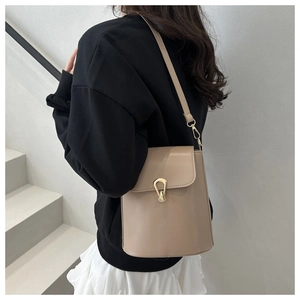 Close-up of beige leather bucket bag with gold buckle on model shoulder for daily outfit