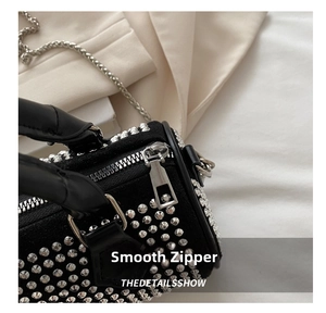 Detailed macro view of silver metal zipper and rivet studs on black suede handbag