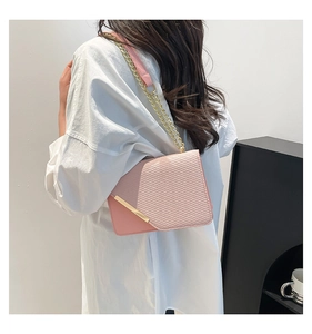 Detail of pink patchwork crossbody bag with gold chain and woven fabric texture
