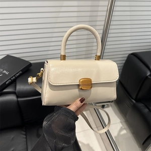 Petit sac à main carré crème avec boucle dorée et poignée sur fond noir contrasté