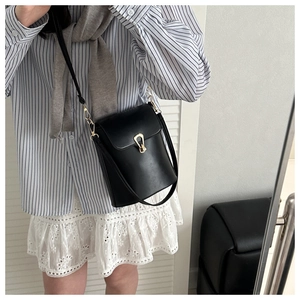 Detail of minimalist black PU leather bucket bag with elegant golden U-shaped metal lock