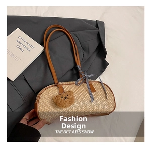 Detailed macro view of woven straw shoulder bag with brown leather handles and bear charm