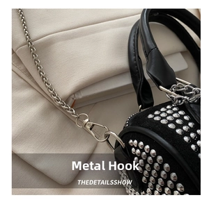 Detail of silver metal hook and chain strap on black studded cylinder handbag