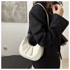 Detail of cream crescent underarm bag featuring dual metal zippers on a black blazer