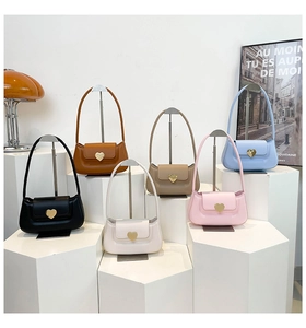 Six different colors of underarm bags with heart-shaped gold buckles on a display stand