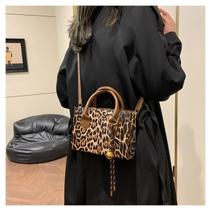 Leopard print large capacity handbag with brown handles and gold charm in lifestyle setting
