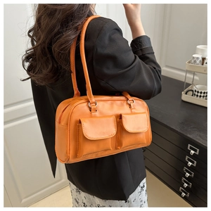 Detail of a bright orange leather shoulder bag featuring two front flap pockets for commuters